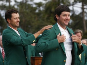 Masters champion Watson is helped with his traditional green jacket by last year's champion Scott of Australia after the final round of the Masters golf tournament at the Augusta National Golf Club in Augusta